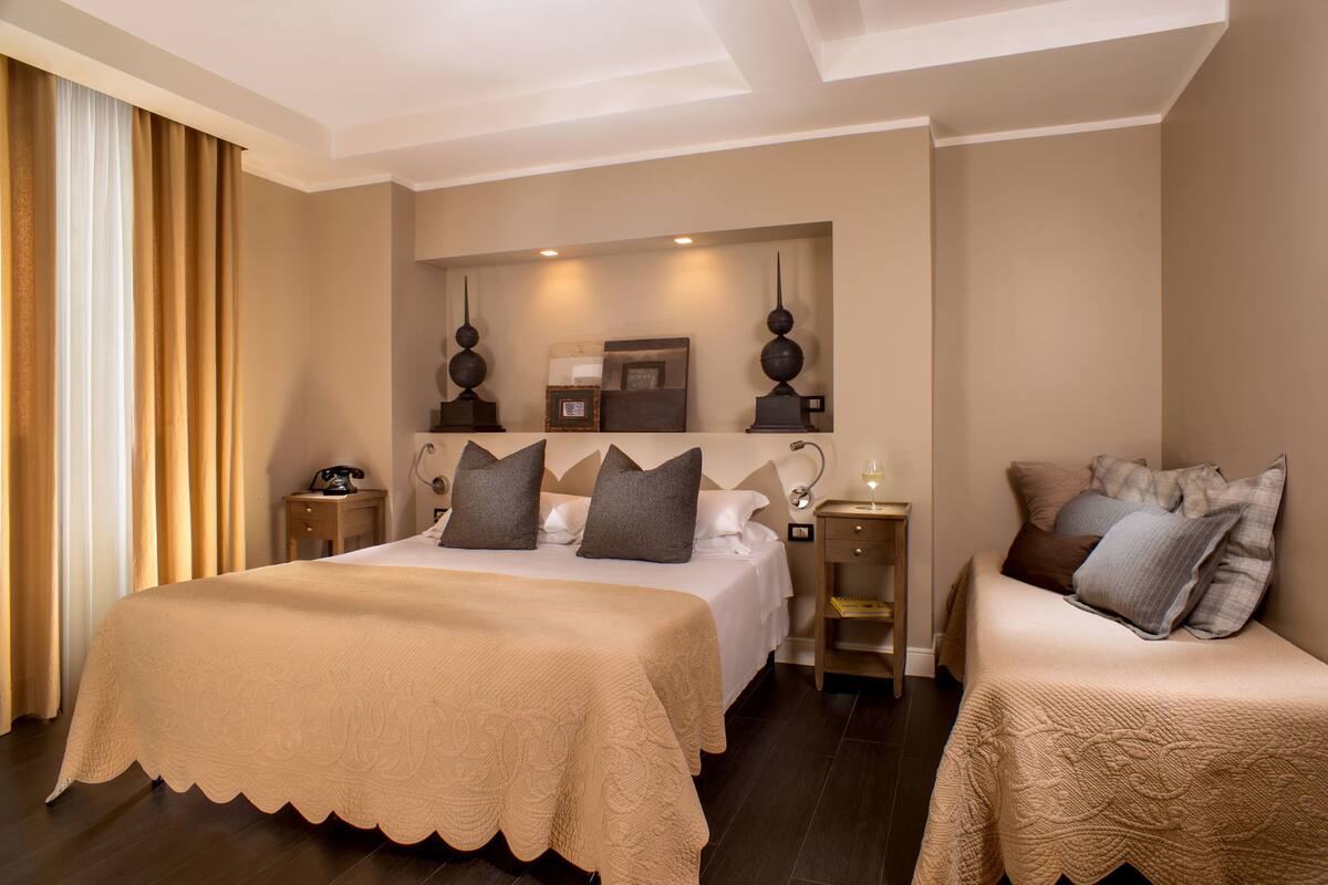 A hotel room with a large bed, two bedside tables, a nightstand, and a mirror above the bed.