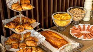 A buffet table with various baked goods including croissants, bread, and a loaf of bread. - The B Place Hotel (Rome)