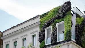 A building with a white facade, green shutters, and a balcony with a metal railing.