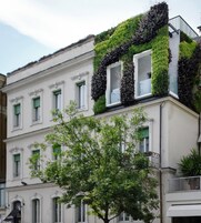 Un edificio con fachada blanca, contraventanas verdes y un balcón con barandilla de metal.