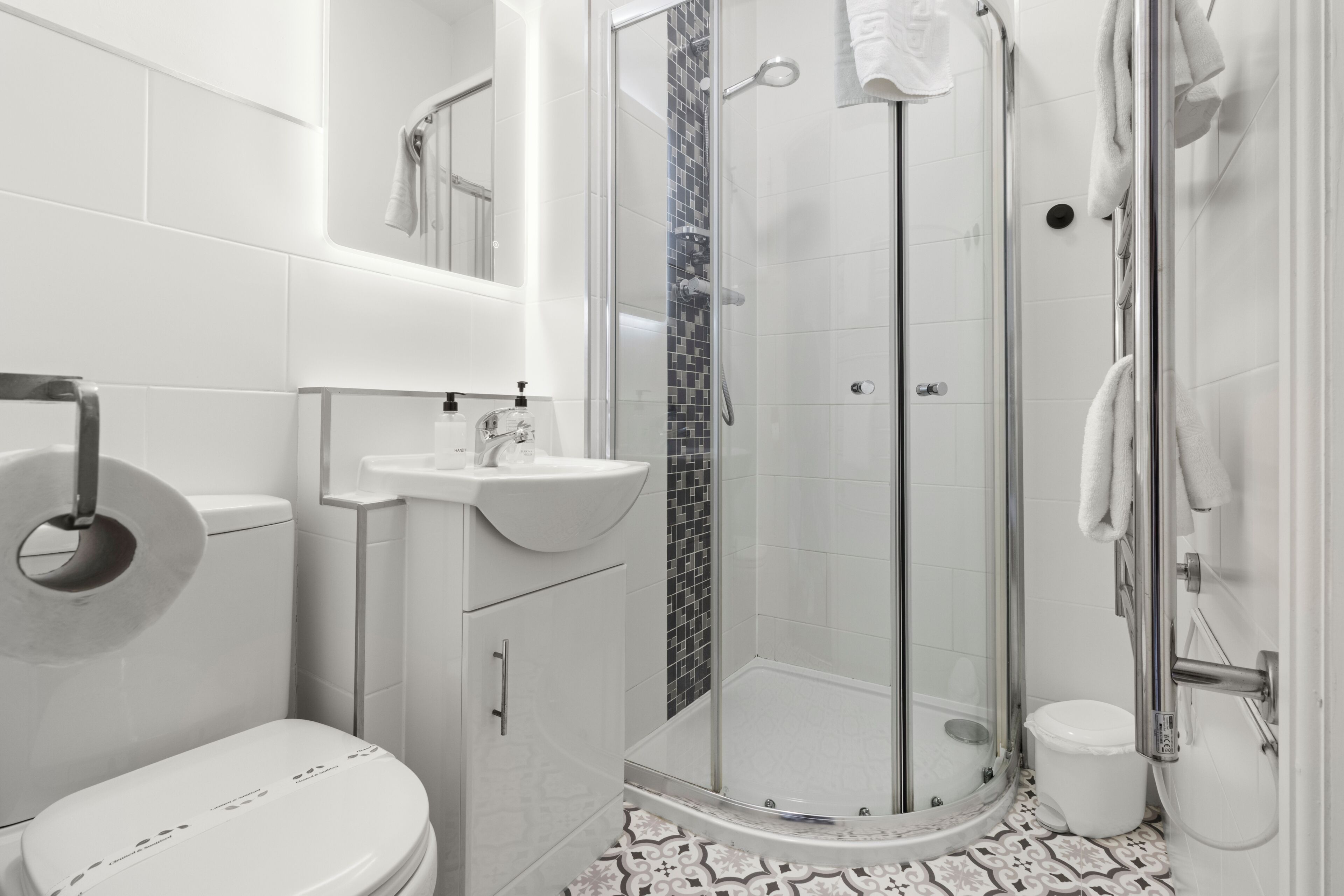 A modern bathroom with a toilet, sink, shower, and glass-enclosed shower stall.