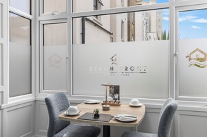 Una habitación con una mesa preparada para dos personas, un detalle decorativo pequeño, y una pared con un logotipo y texto.