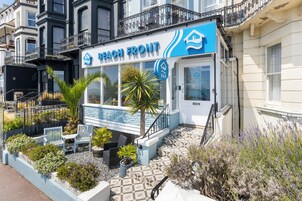 Una propiedad frente a la playa con un letrero que dice 'Beach Front', piscina, mobiliario exterior y una escalera que lleva a la entrada.