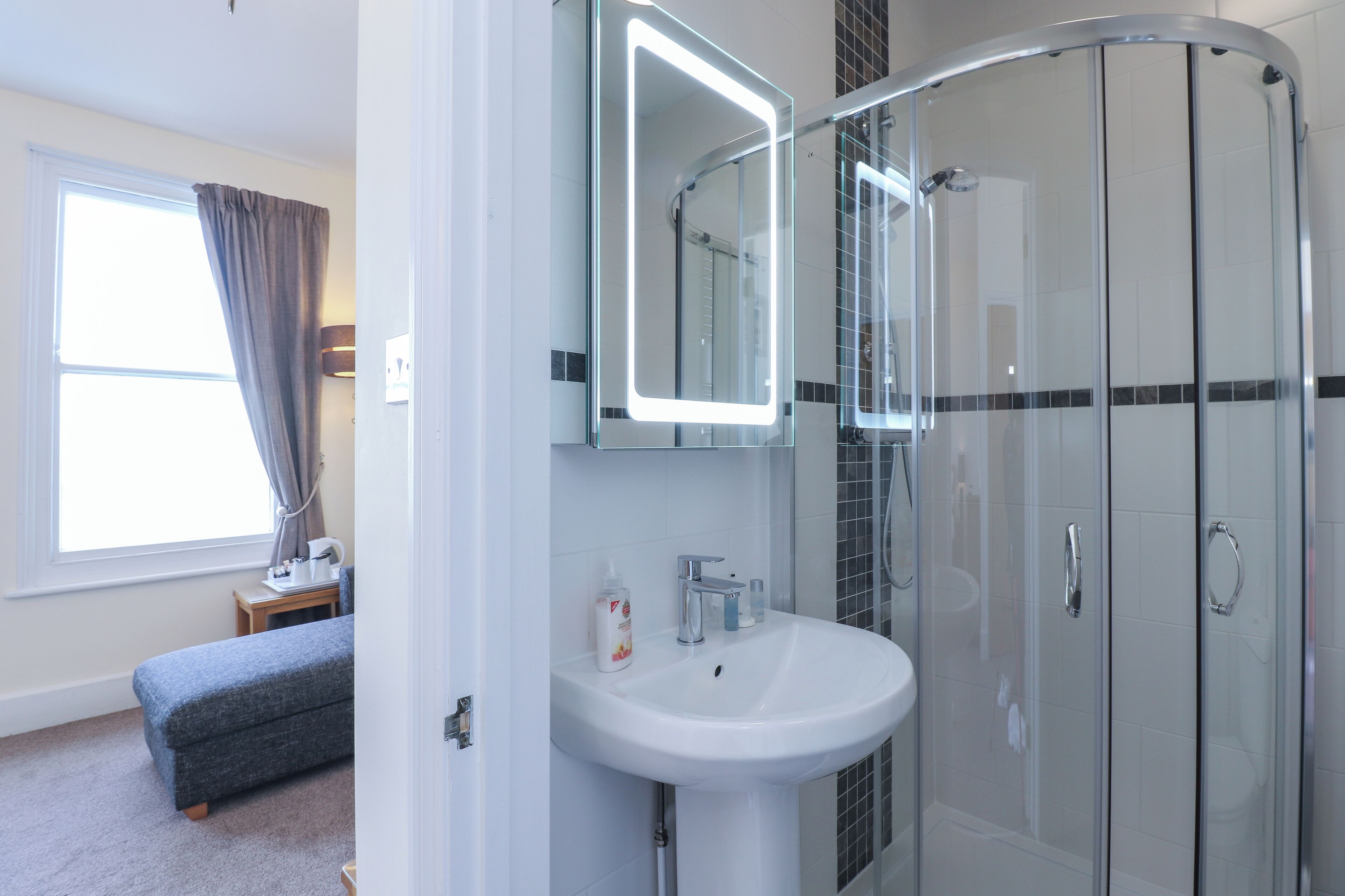 A modern bathroom with a glass shower enclosure, a white sink, and a vanity with a mirror.