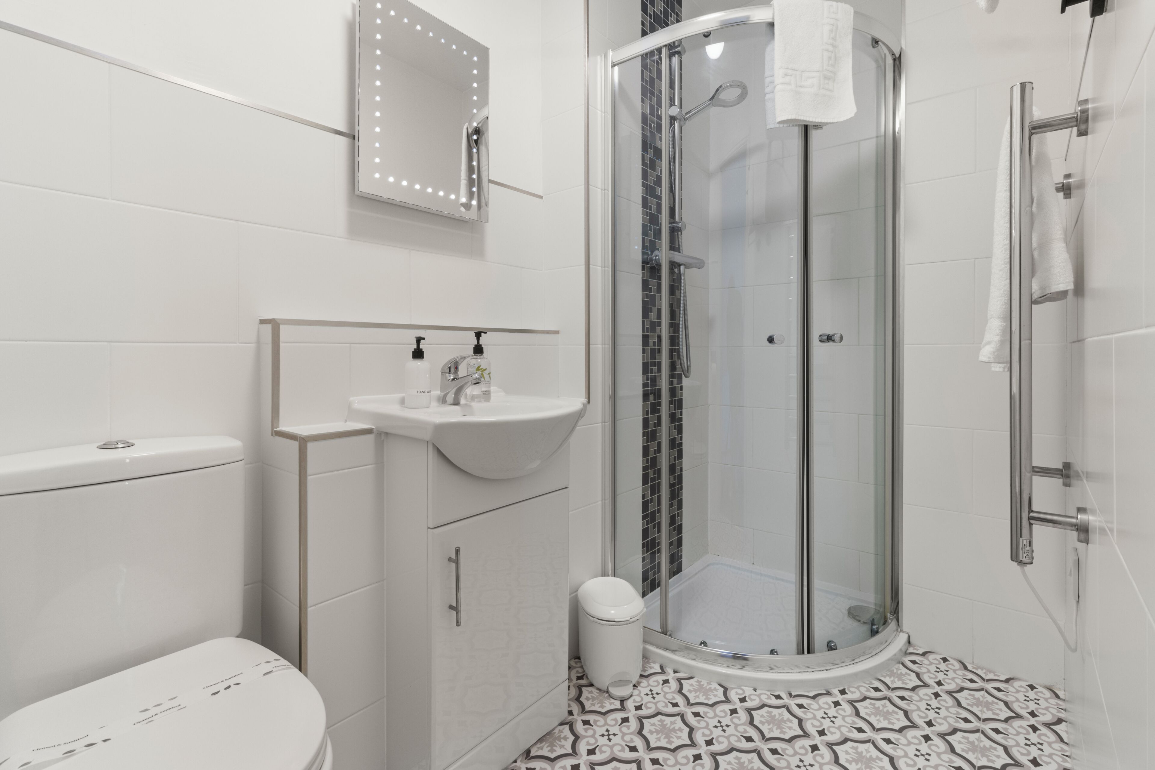 A modern bathroom with a glass-enclosed shower, a white sink, and a toilet.