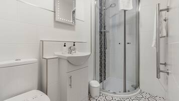 A modern bathroom with a glass-enclosed shower, a white sink, and a toilet.