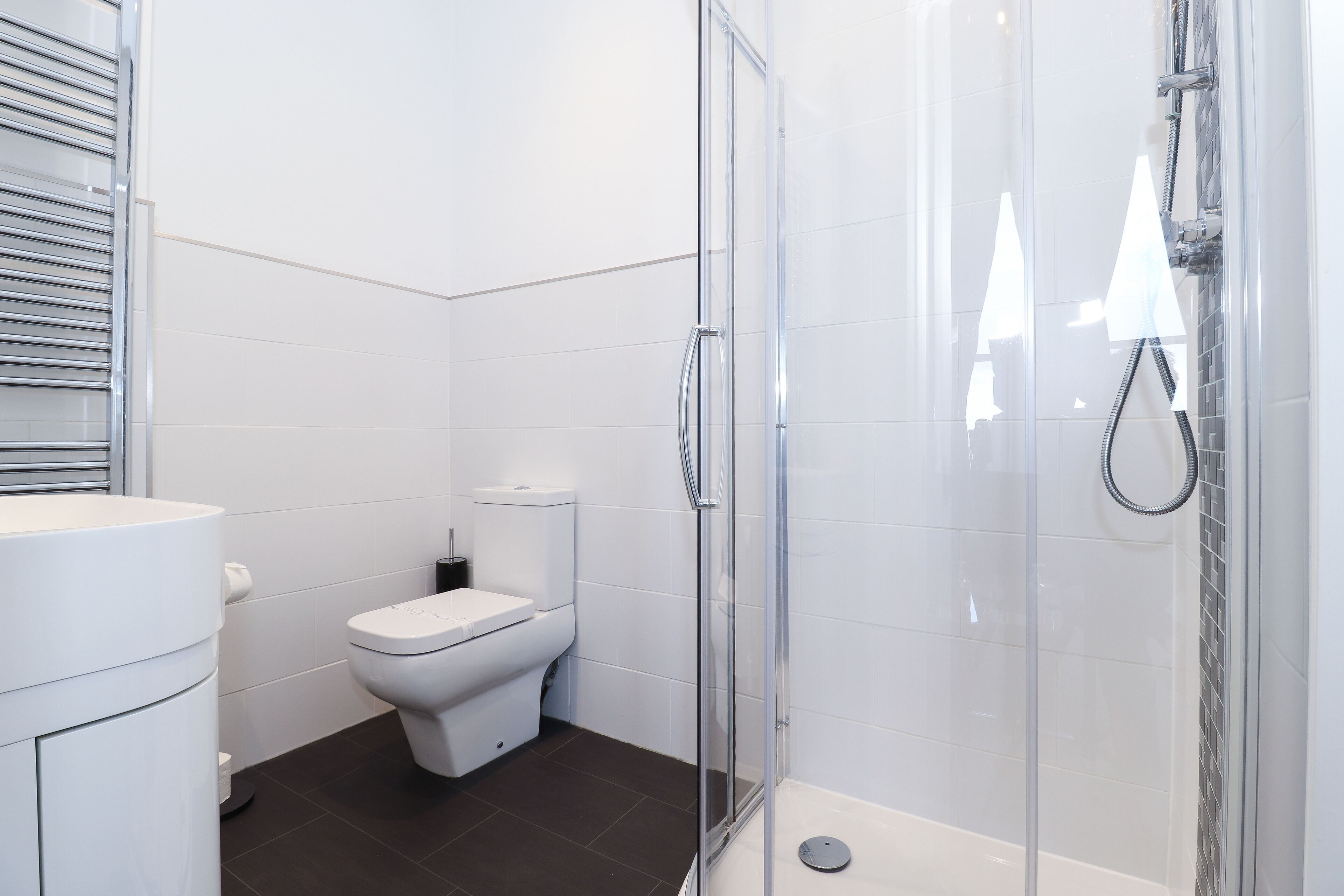A modern bathroom with a toilet, a shower enclosure, and a sink.