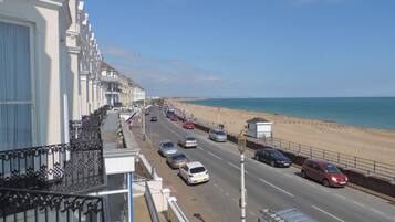 A coastal road with cars, a beach, and white buildings.