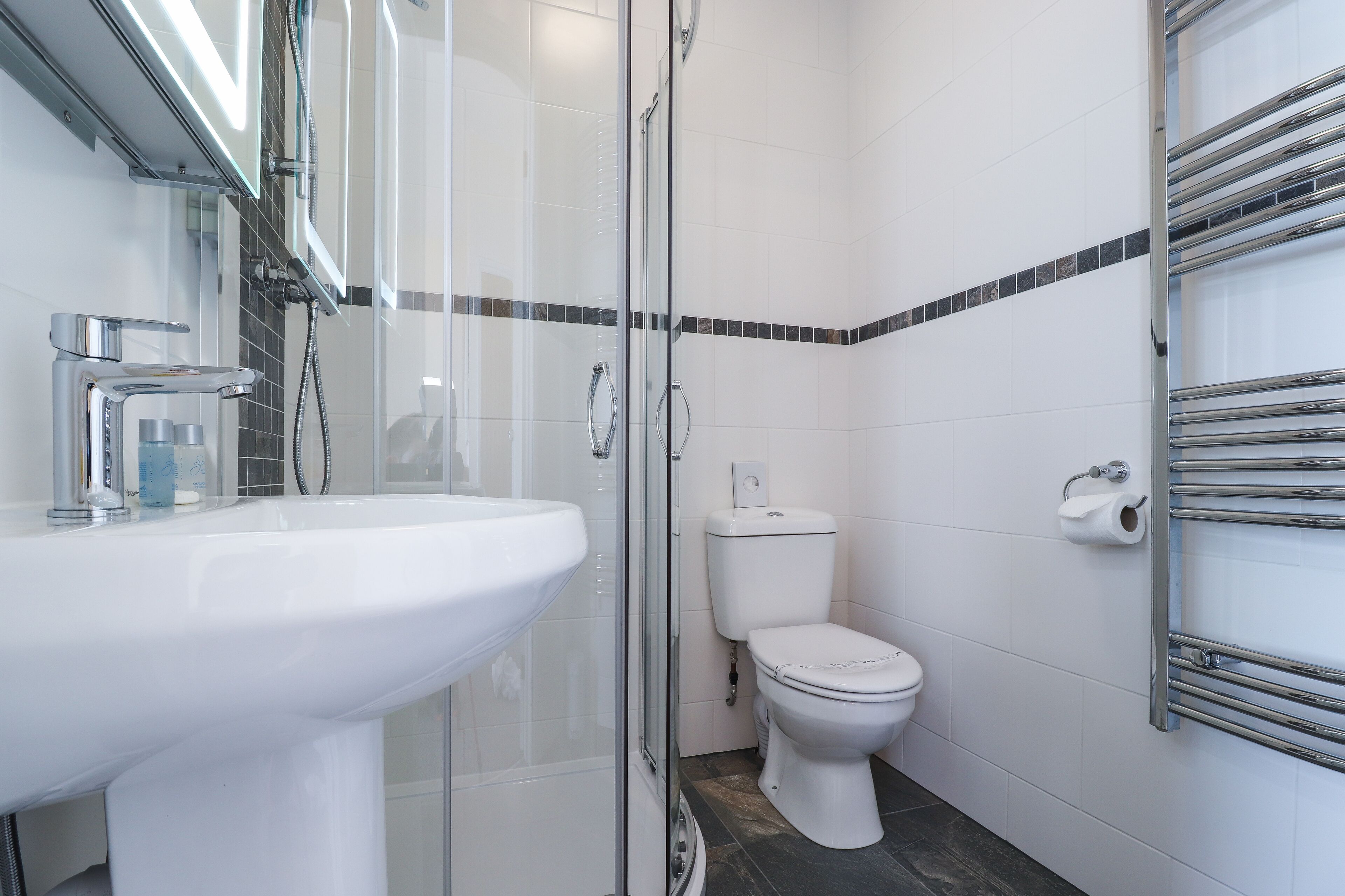 A modern bathroom with a glass-enclosed shower, a white sink, and a toilet.