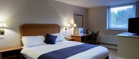 Une chambre d’hôtel avec un grand lit, des lampes de chevet, un bureau avec un ordinateur et une télévision.