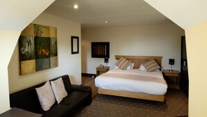 A hotel room with a large bed, a sofa, a painting on the wall, and a TV. - The Cathedral Hotel (Lichfield)
