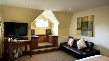 A cozy room with a TV, wooden desk, and a sofa.