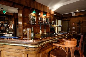 A bar area with wooden paneling, multiple taps, and a variety of bottles. - The Cathedral Hotel (Lichfield)