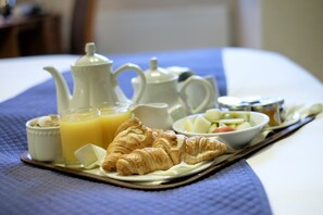 A breakfast tray with croissants, orange juice, and a teapot on a bed. - The Cathedral Hotel (Lichfield)