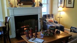 Una sala de estar acogedora con chimenea, un sillón cómodo, una mesa de centro con adornos y un comedor con mesa y sillas.
