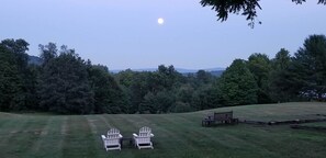 Un espacio al aire libre con césped, dos sillas Adirondack y un banco de madera.