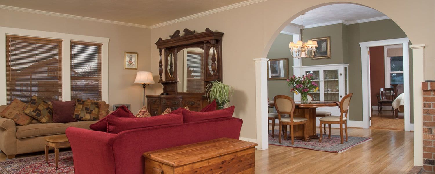 A living room with a red sofa, a wooden coffee table, and a dining area with a wooden table and chairs.