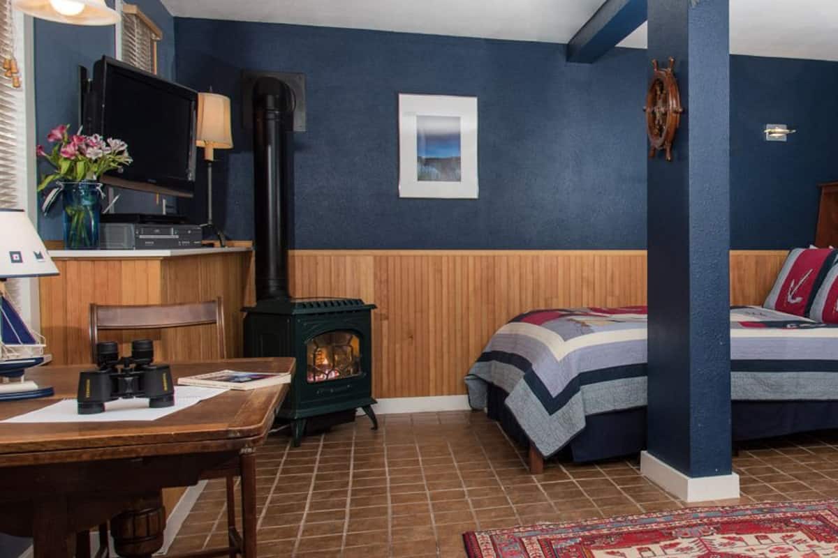 Une chambre à coucher avec un lit en bois, un bureau avec une lampe, une télévision et une armoire.