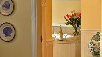 A doorway leading to a room with a wine bottle and glasses on a counter, a vase with red roses, and decorative plates on the wall.