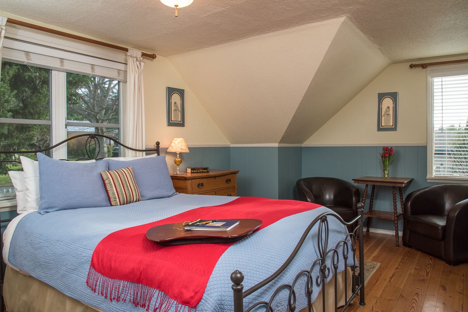 A bedroom with a bed, a nightstand, a chair, a table, and a window.