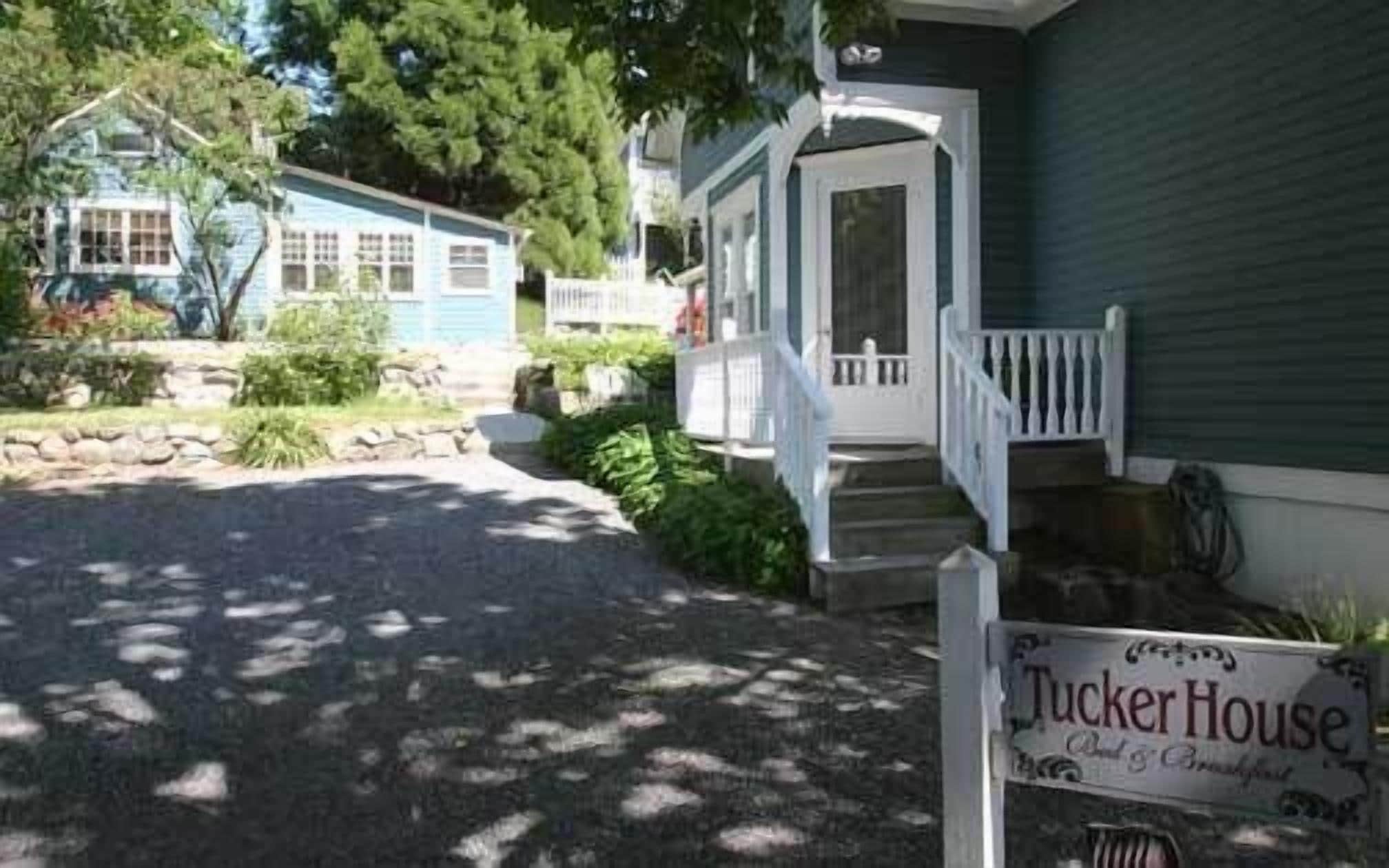 A house with a porch and a sign that reads "Tucker House."