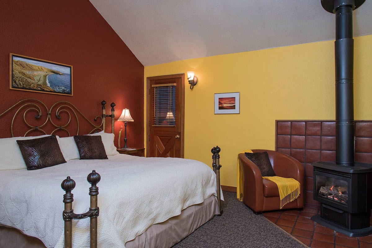 Une chambre à coucher avec un lit, une chaise, une cheminée, une lampe et une porte.
