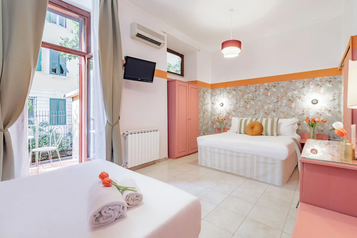 A hotel room with a bed, a desk, a TV, and a window with curtains.