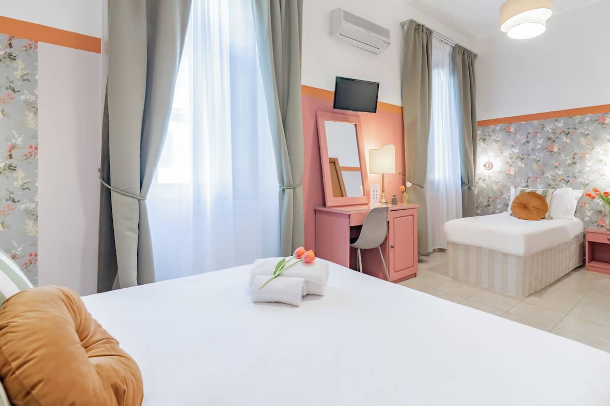 A hotel room with a bed, a desk, a chair, a TV, and a window with curtains.