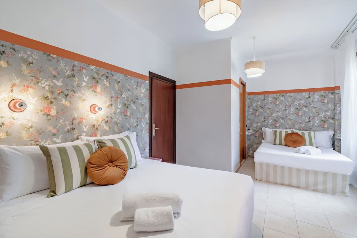 A hotel room with a large bed, a smaller bed, and a bathroom.