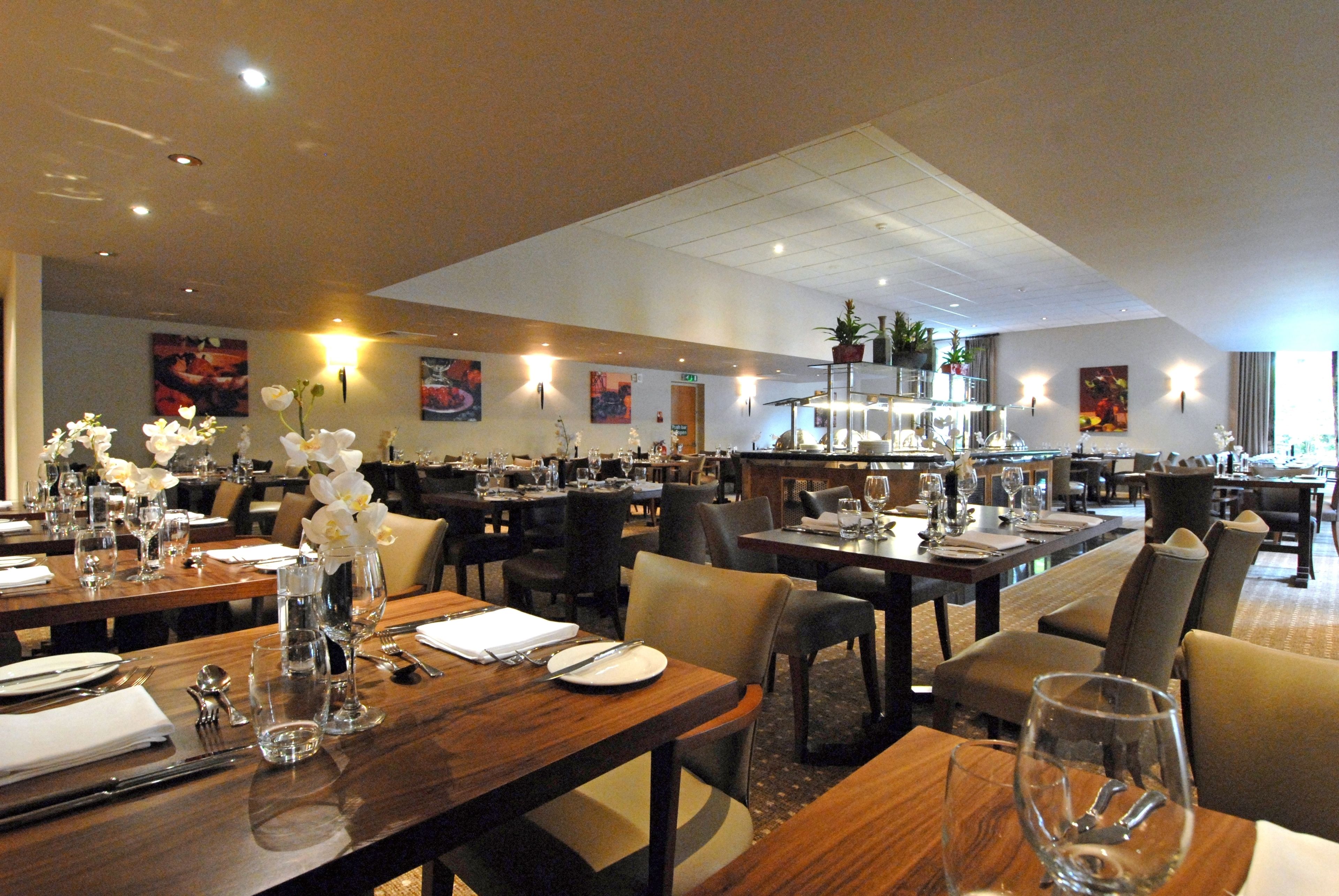 A spacious restaurant with multiple dining tables, chairs, and a variety of table settings.