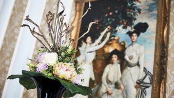 A vase with flowers and dried branches in a room with a painting on the wall.