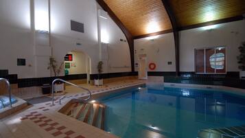 An indoor swimming pool with a tiled floor, a wooden ceiling, and a lifebuoy on the wall.