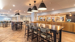 A restaurant with wooden flooring, black pendant lighting, and a bar area with a counter and various items on display. - Sedgebrook Hall (Northampton)