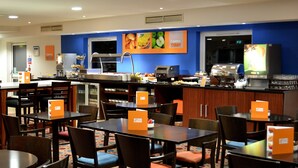 A hotel restaurant with multiple tables and chairs, a buffet area, and a coffee station. - Holiday Inn Express Braintree by IHG (Braintree)