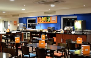 A hotel restaurant with multiple tables and chairs, a buffet area, and a coffee station. - Holiday Inn Express Braintree by IHG (Braintree)
