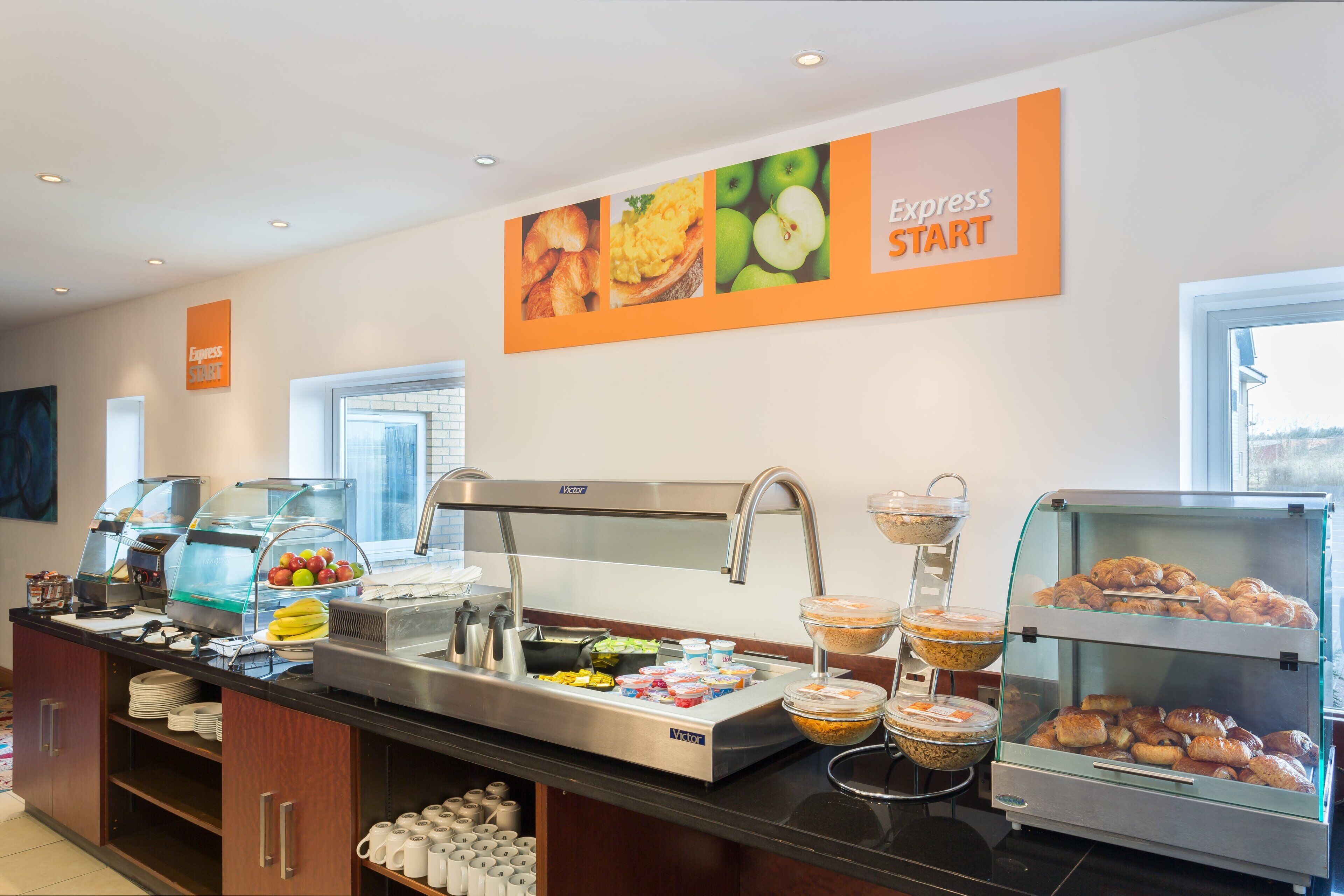 Zona de bufé con diversas opciones de comida, incluyendo frutas, pasteles y bebidas.