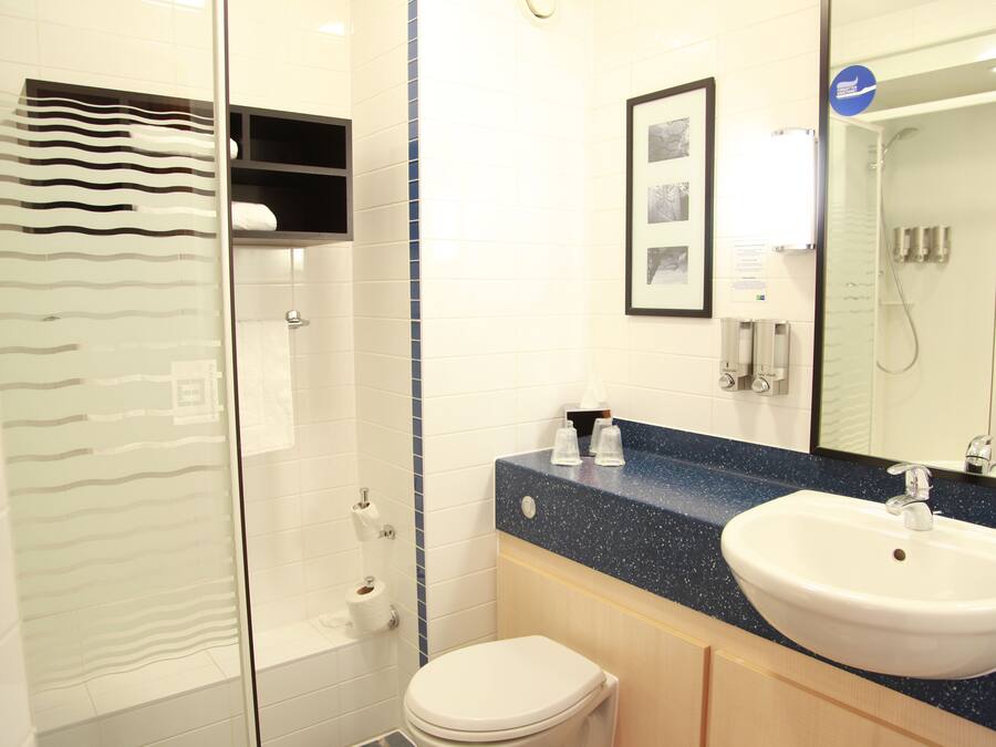 A modern bathroom with a shower, toilet, sink, and a mirror.