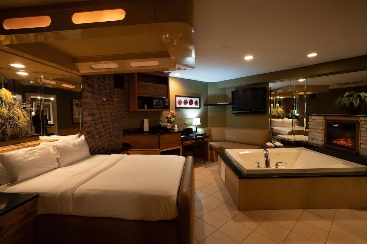 Une chambre d’hôtel dotée d’un grand lit, d’un coin salon séparé, d’une salle de bain avec baignoire et d’un téléviseur fixé au mur.