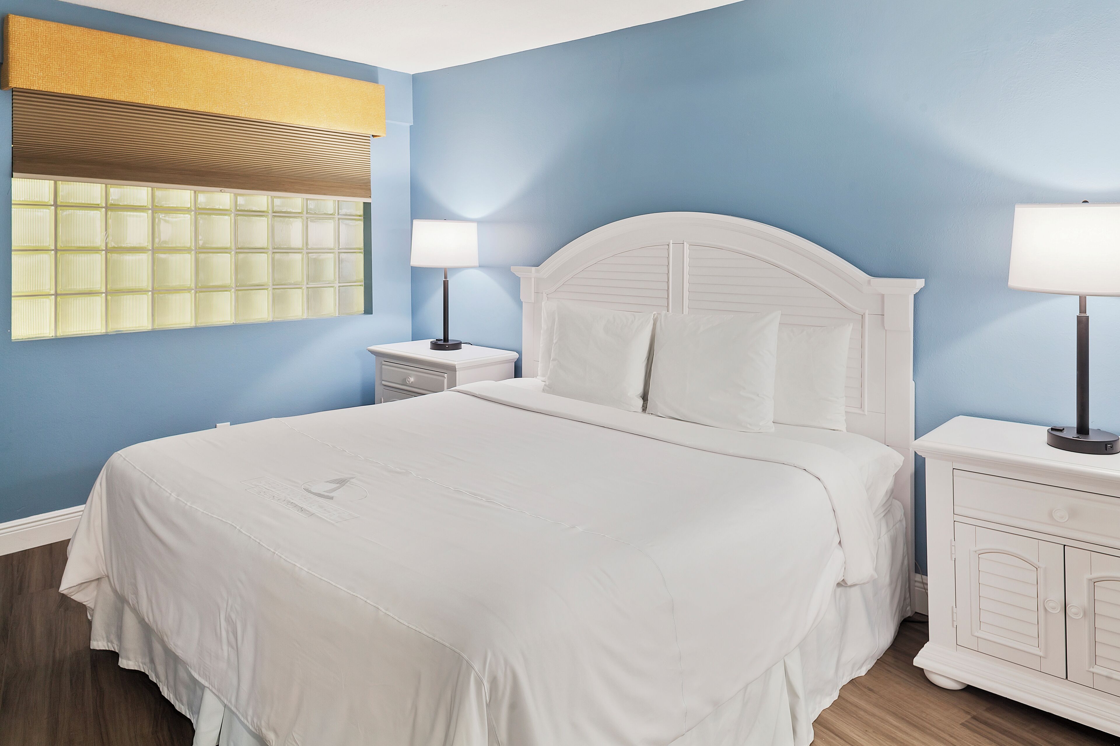 Une chambre à coucher avec un lit, des tables de chevet et une fenêtre avec des stores.