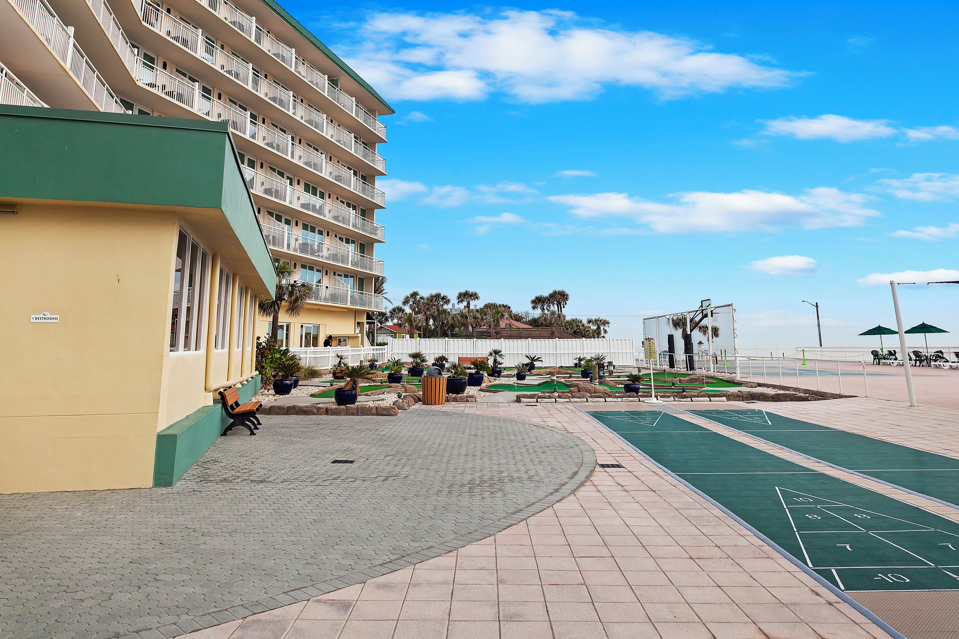 A courtyard with a shuffleboard court, benches, and a building with balconies.