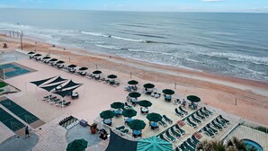 Un patio frente a la playa con mobiliario exterior y vistas al océano.
