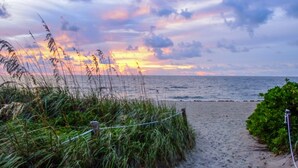 A beach path with a fence and vegetation, leading to the sea under a colorful sunset sky. - Sea Cliff Motel (Lauderdale-by-the-Sea)
