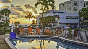 A pool area with lounge chairs and a view of the ocean at sunset. - Sea Cliff Motel (Lauderdale-by-the-Sea)