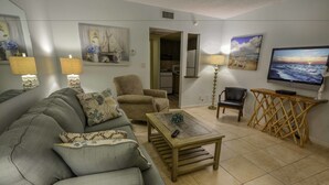 A living room with a sofa, armchair, coffee table, TV, and artwork on the walls. - Sea Cliff Motel (Lauderdale-by-the-Sea)