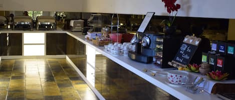 A coffee station with multiple coffee machines, a variety of coffee cups, and a sign indicating the coffee stand.