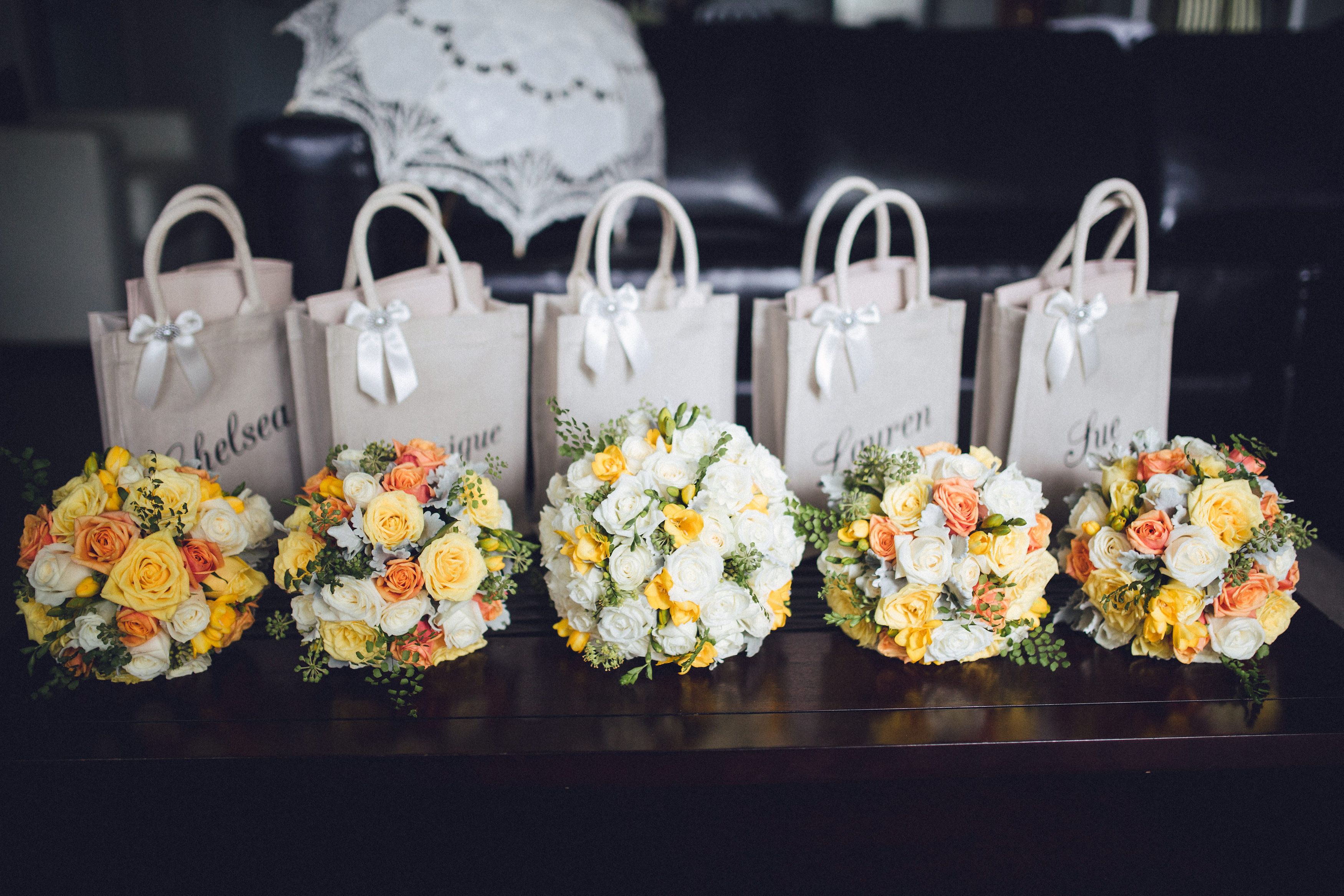 Five wedding gift bags with bouquets on a table.