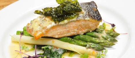A plate of food with a piece of fish, asparagus, and greens.