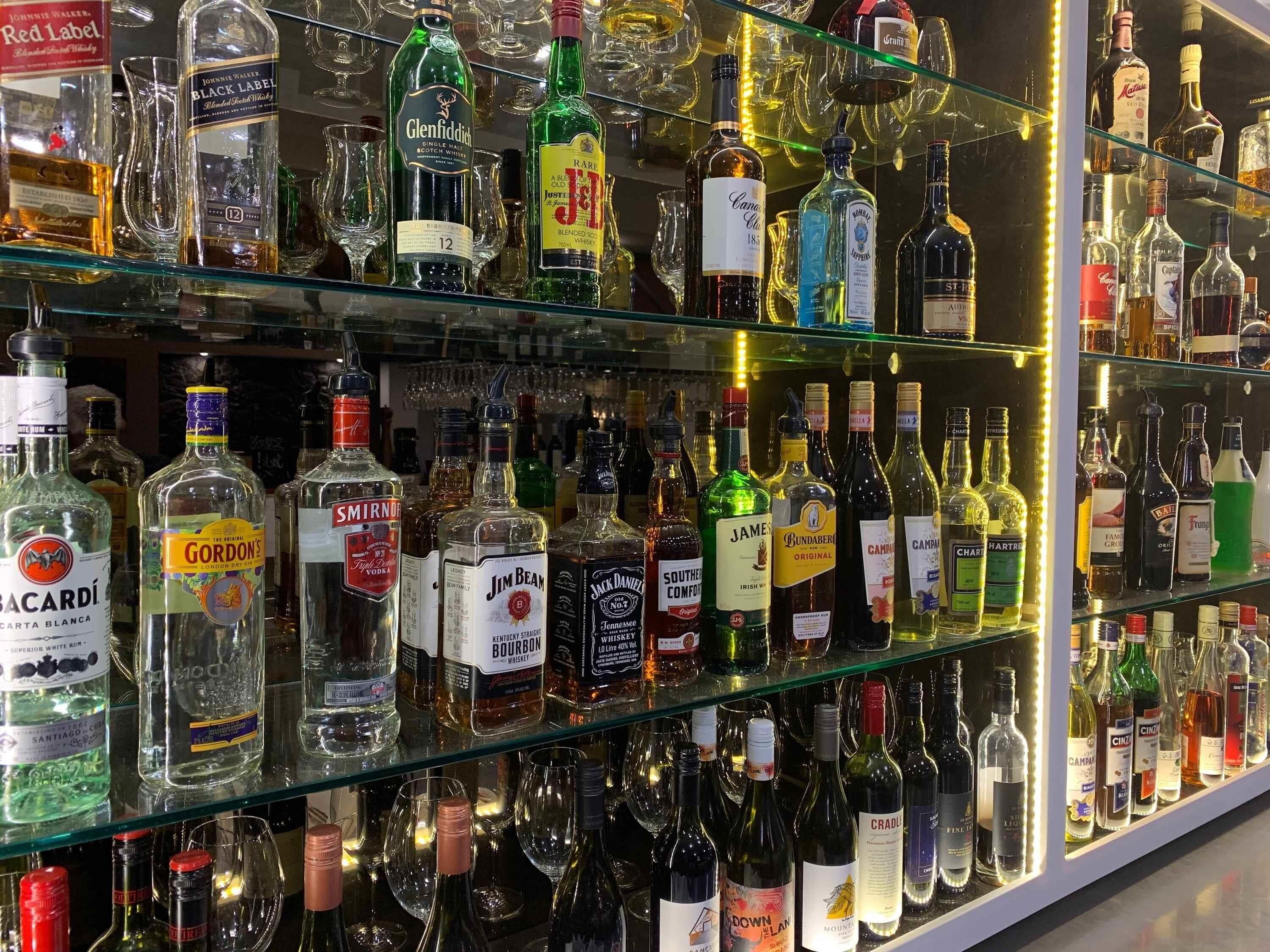 Un bar dont les étagères sont remplies de différentes bouteilles d’alcool et de verres.