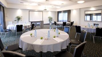 A conference room with round tables, chairs, and a projector screen.