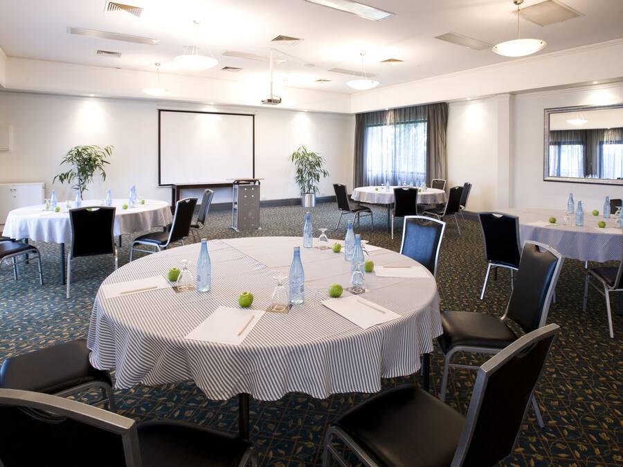 A conference room with round tables, chairs, and a projector screen.